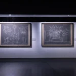 Two Keith Haring Subway Drawings in white chalk on black paper, shown in a room recreating a New York subway station