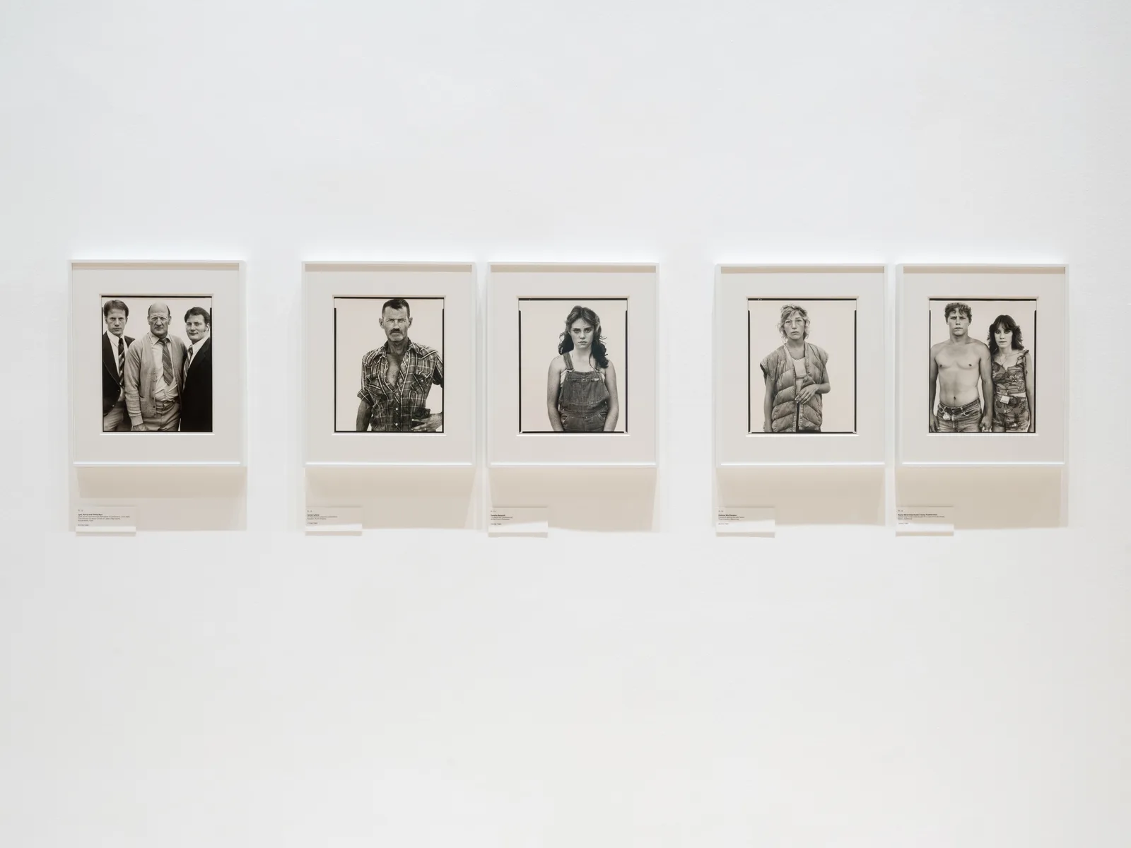 Five black and white portraits from Richard Avedon’s In the American West hanging in white frames on a white gallery wall
