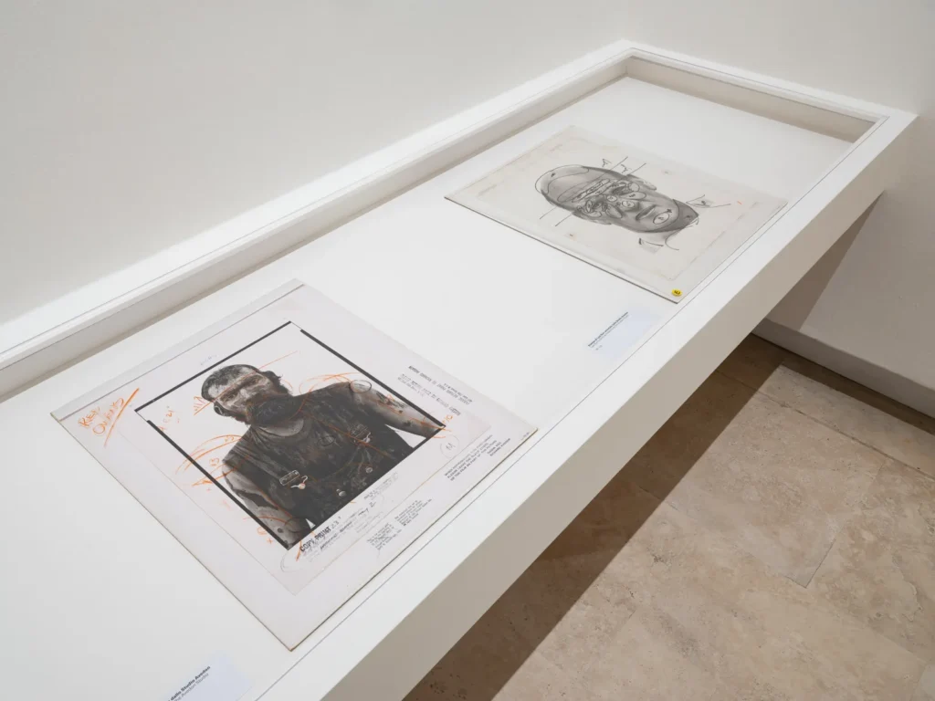 Glass display case holding two Avedon work prints covered in handwritten printing notes and markings from the Avedon Studio